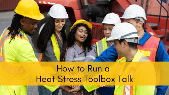A work crew in hard hats and high visibility vests gathered in a circle for a pre-shift heat stress toolbox talk at an industrial site